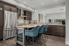 Une cuisine moderne dotée d’appareils électroménagers en acier inoxydable, de meubles de rangement en bois foncé et d’un îlot central agrémenté de tabourets de bar.