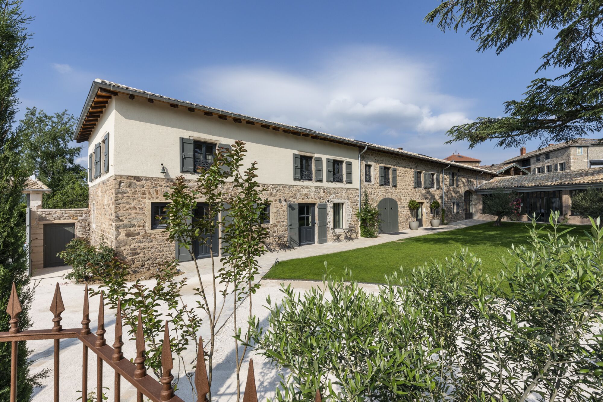 A two-story stone building with a flat roof, multiple windows, and a well-maintained lawn.