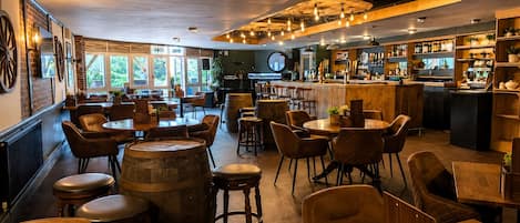 A bar area with wooden furniture, a bar counter, and a seating area with round tables and chairs.
