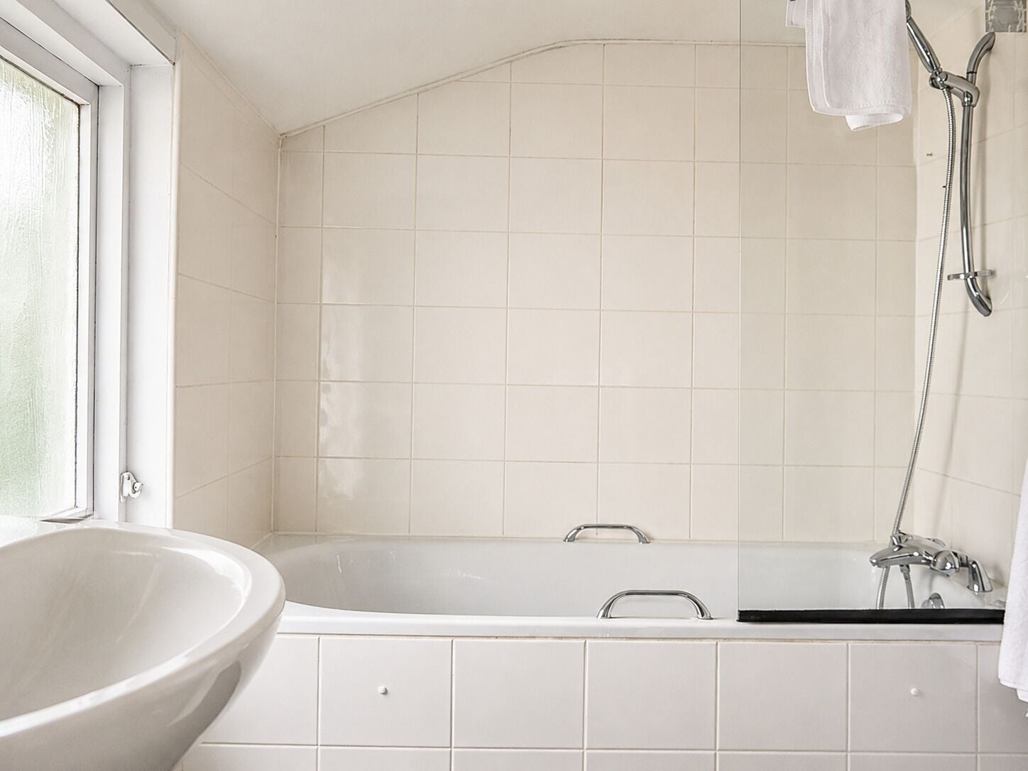 Een badkamer met een vrijstaand bad, een raam en een douchegedeelte.