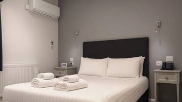 Una camera d'albergo moderna con un letto grande, due comodini, un condizionatore d'aria e un termostato.