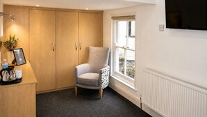 A room with a wooden wardrobe, a grey armchair, a coffee station, a radiator, and a TV on the wall. - The Park Hotel, Sure Hotel Collection by Best Western (Diss)