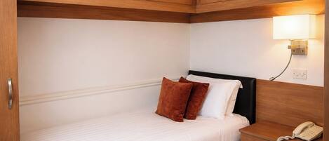 A hotel room with a bed, a bedside telephone, and a wall-mounted light.