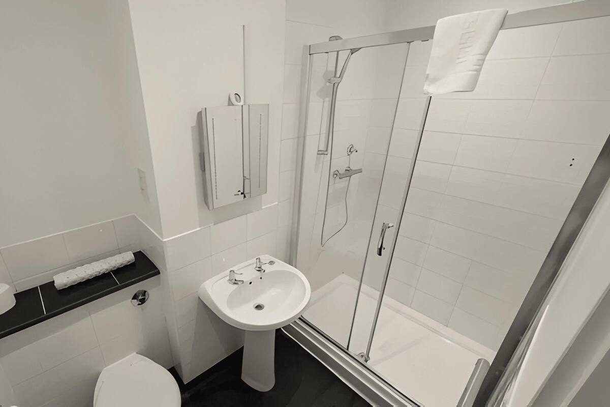 A modern bathroom with a toilet, sink, and glass-enclosed shower.