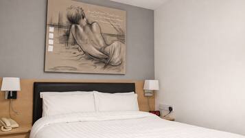 A hotel room with a bed, bedside lamps, a telephone, and a wall-mounted artwork.