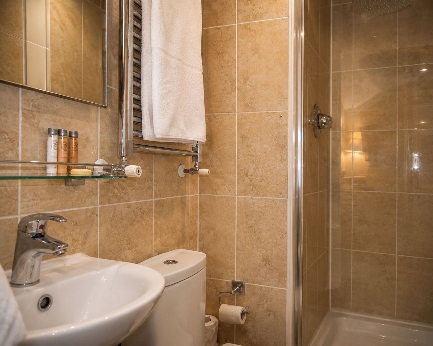 A bathroom with a sink, toilet, and glass shower enclosure.