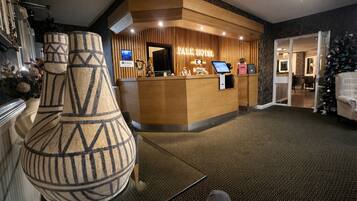 Zona de recepción de un hotel con mostrador de madera, pantalla digital y un árbol de Navidad.