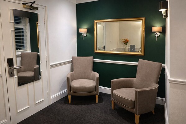 A hallway with two armchairs, a mirror, and wall sconces. - The Park Hotel, Sure Hotel Collection by Best Western (Diss)