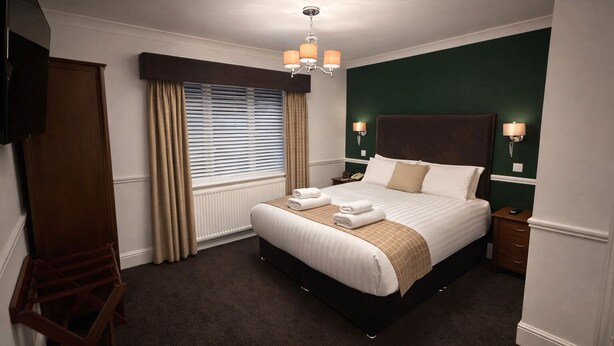 A hotel room with a large bed, a wooden wardrobe, a desk, and a television. - The Park Hotel, Sure Hotel Collection by Best Western (Diss)