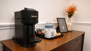 A Nespresso coffee machine on a wooden counter with a tray of coffee cups, water bottles, and a framed menu. - The Park Hotel, Sure Hotel Collection by Best Western (Diss)