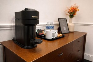 A Nespresso coffee machine on a wooden counter with a tray of coffee cups, water bottles, and a framed menu. - The Park Hotel, Sure Hotel Collection by Best Western (Diss)