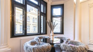 Une pièce avec une table ronde, des fauteuils recouverts de fourrure et un vase orné de plumes.
