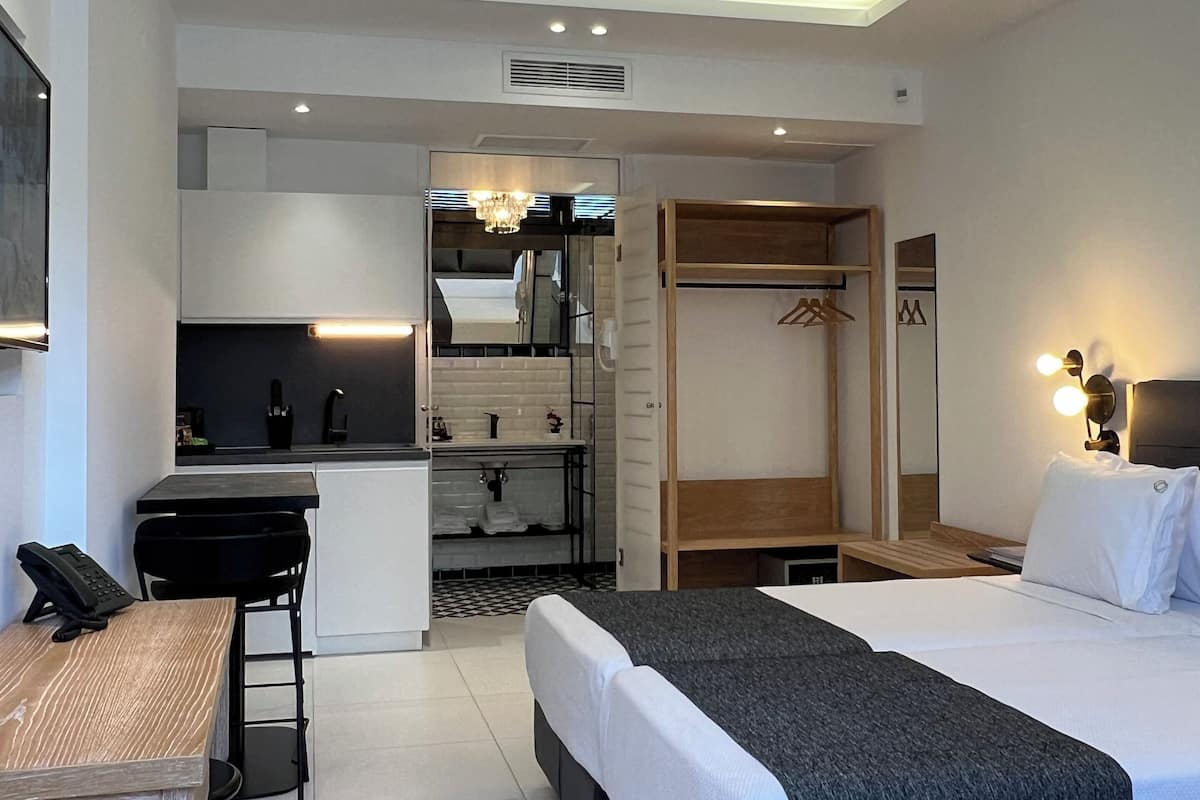 Ett modernt hotellrum med en säng, ett nattduksbord, ett skrivbord och en inbyggd garderob.