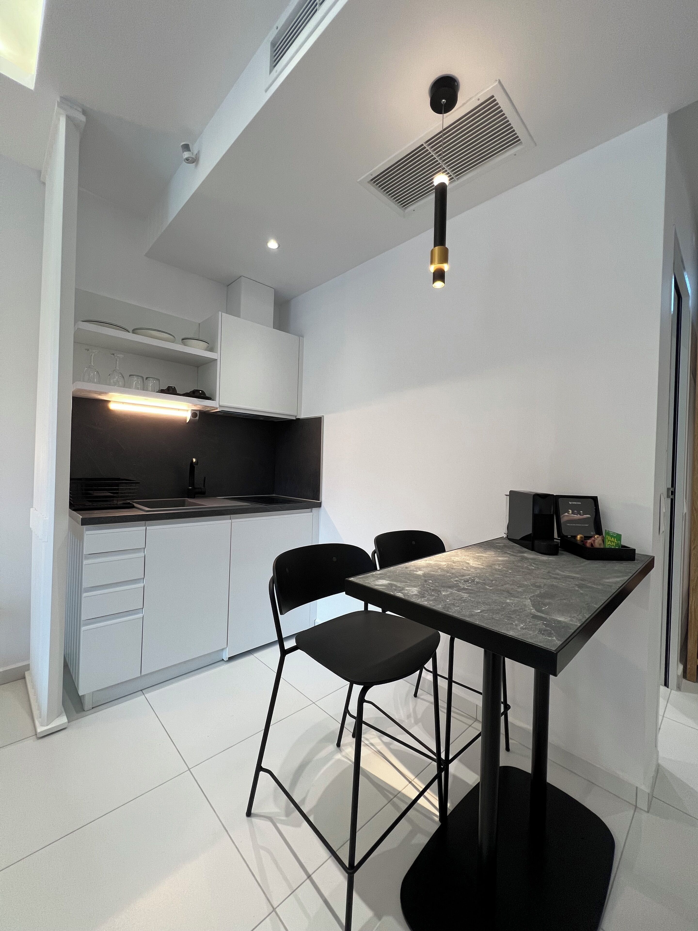 A modern kitchen with white cabinets, a black countertop, and a dining area with a marble table and black chairs.