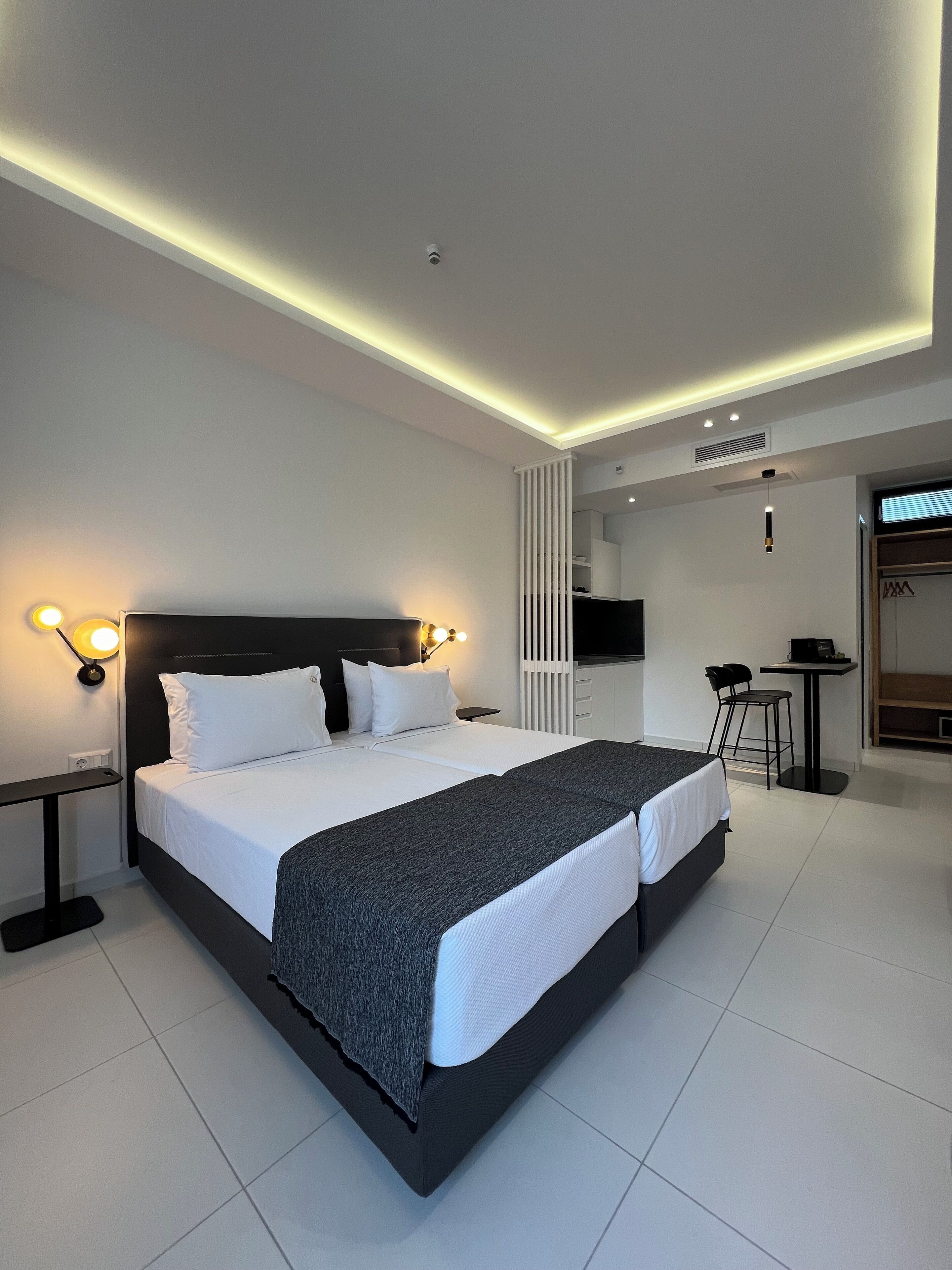 A modern hotel room with a large bed, bedside tables, a desk, and a seating area.