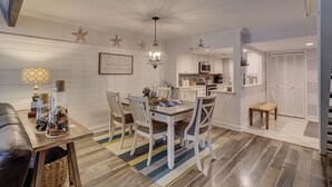 Ein Essbereich mit einem Holztisch und Stühlen, einer Kristallleuchtre und einer Küche im Hintergrund.