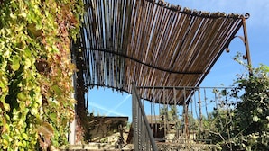 Uma escadaria com toldo de bambu e paredes cobertas de hera.