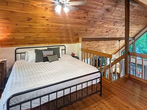A bedroom with a bed, wooden ceiling, and a balcony.
