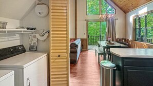 Una cocina moderna con armarios de madera, un comedor con mesa y sillas, y vistas a zonas verdes.