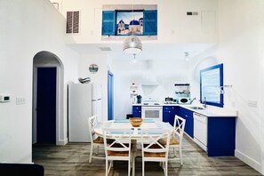 Eine kompakte Küche mit Essbereich, ausgestattet mit einer zentralen Kochinsel, weißen Schränken und blauen Akzenten.