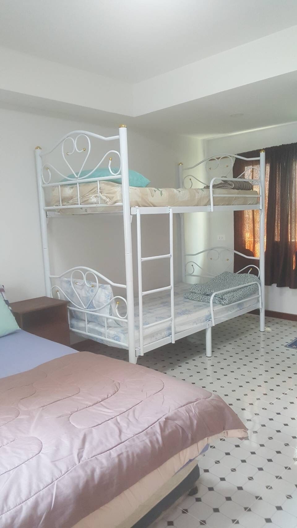 A bunk bed room with a single bed, a small table, and a patterned floor.