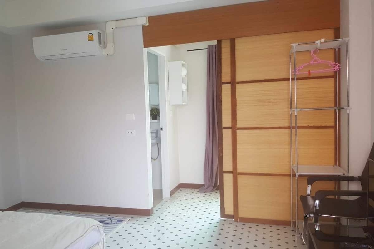 Une chambre d’hôtel équipée d’un lit, d’une armoire, d’un bureau avec une chaise et d’un appareil de climatisation.