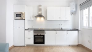 A modern kitchen with white cabinets, a stainless steel microwave, oven, and a gas stove.