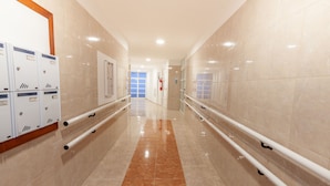 A corridor with lockers, a fire extinguisher, and a door at the end.