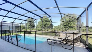 A covered swimming pool with a patio area, including lounge chairs and a table. - Magical Express: Private Pool & 24/7 Support (Davenport)