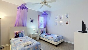 Une chambre avec deux lits, un ventilateur de plafond, des lampes de chevet, un bureau et un téléviseur.