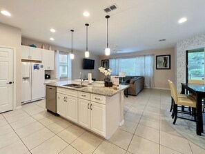 A modern kitchen with a central island, white cabinetry, and pendant lighting.