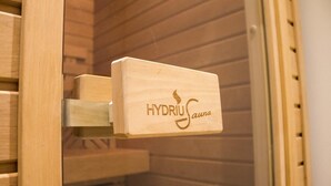 En bastudörr av trä med inskriptionen ”HYDRIUS Sauna”.