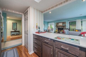 A modern kitchen with a large island, wooden cabinets, and a view into the living area. - Bent Creek 28 at Rumbling Bald (Lake Lure)
