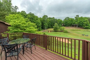 A wooden deck with a glass table and chairs, overlooking a golf course. - Bent Creek 28 at Rumbling Bald (Lake Lure)