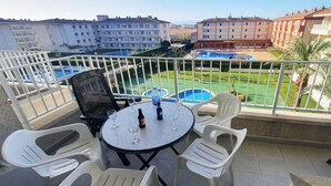 Ein Balkon mit Tisch, Stühlen und Blick auf einen Swimmingpool und Gebäude.