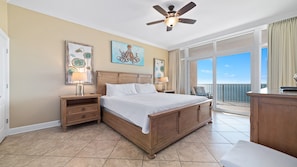 A bedroom with a large bed, wooden headboard, two bedside tables with lamps, and artwork on the walls.