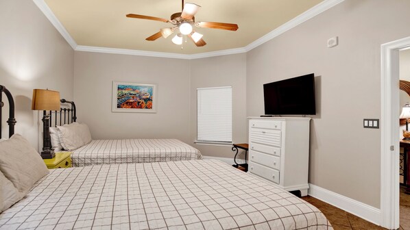A bedroom with two beds, a ceiling fan, a TV, a dresser, and a painting on the wall. - New to the Rental Market, Beachfront, Lazy River and Slide!! (Orange Beach)