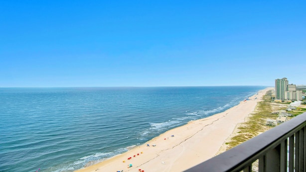 Ein Strand mit Blick auf den Ozean und einem Hotel im Hintergrund.