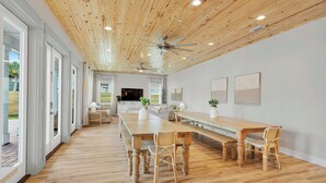 A spacious dining area with a long wooden table, wicker chairs, and a ceiling fan. - Poseidon's Palace | Private Pool/Spa | 6-Seater Golf Cart | Game Room (Destin)
