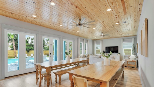 A spacious living area with a wooden ceiling, large windows, a pool view, and a TV. - Poseidon's Palace | Private Pool/Spa | 6-Seater Golf Cart | Game Room (Destin)