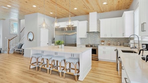 A modern kitchen with a central island, white cabinetry, and a wooden ceiling. - Poseidon's Palace | Private Pool/Spa | 6-Seater Golf Cart | Game Room (Destin)