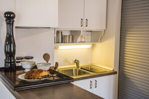 A kitchen with white cabinets, stainless steel appliances, and a countertop with a plate of croissants.