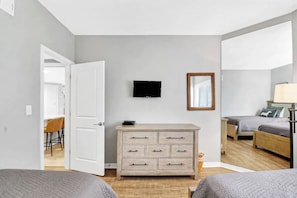 Een slaapkamer met een bed, een dressoir, een televisie en een spiegel.