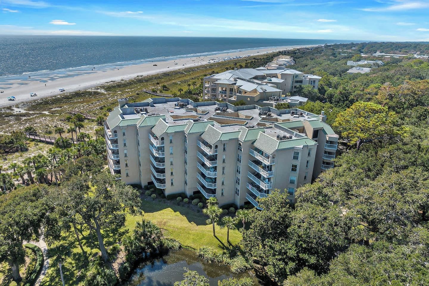 Un hôtel à plusieurs étages doté d’une cour intérieure, entouré d’une végétation luxuriante et offrant une vue sur la plage.