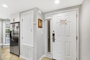 A hallway with a stainless steel refrigerator, a white door with a window, and a door with a window and a small picture. - Oceanfront Villa Direct Beach Access (Hilton Head Island)