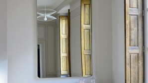 A room with a large mirror, a white console table with decorative glass jars, and a vintage-style ceiling fan. - Spacious apartment in old Lyon historical location (Lyon)