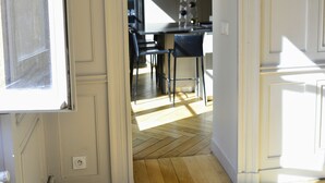 A hallway with a wooden herringbone floor leading to a kitchen area with a dining table and chairs. - Spacious apartment in old Lyon historical location (Lyon)