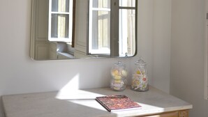 A room with a large mirror on the wall, a wooden vanity table, and two glass jars with items inside. - Spacious apartment in old Lyon historical location (Lyon)
