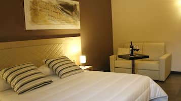 A hotel room with a large bed, a bedside table, a chair, and a wall-mounted artwork.