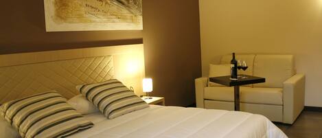 A hotel room with a large bed, a bedside table, a chair, and a wall-mounted artwork.